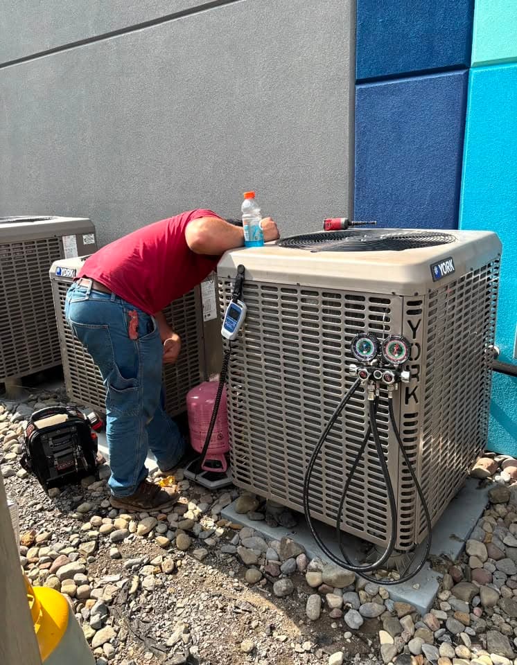 Martelli & Son technician servicing a York AC condenser with manifold gauges