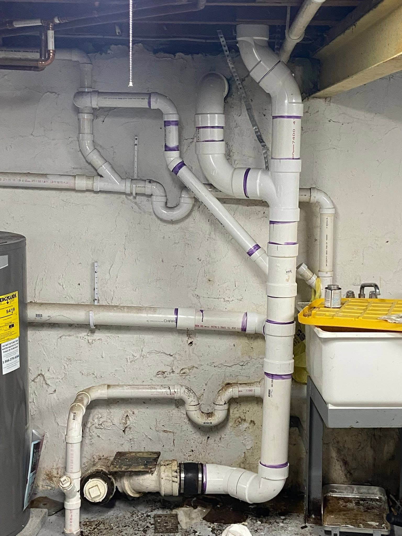 Freshly installed PVC drain and vent plumbing in a basement